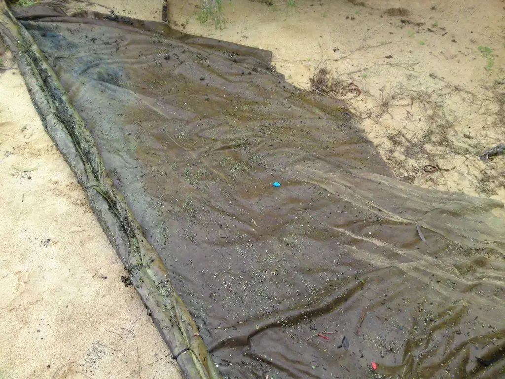 Saturated oil-absorbing mat on sand after use