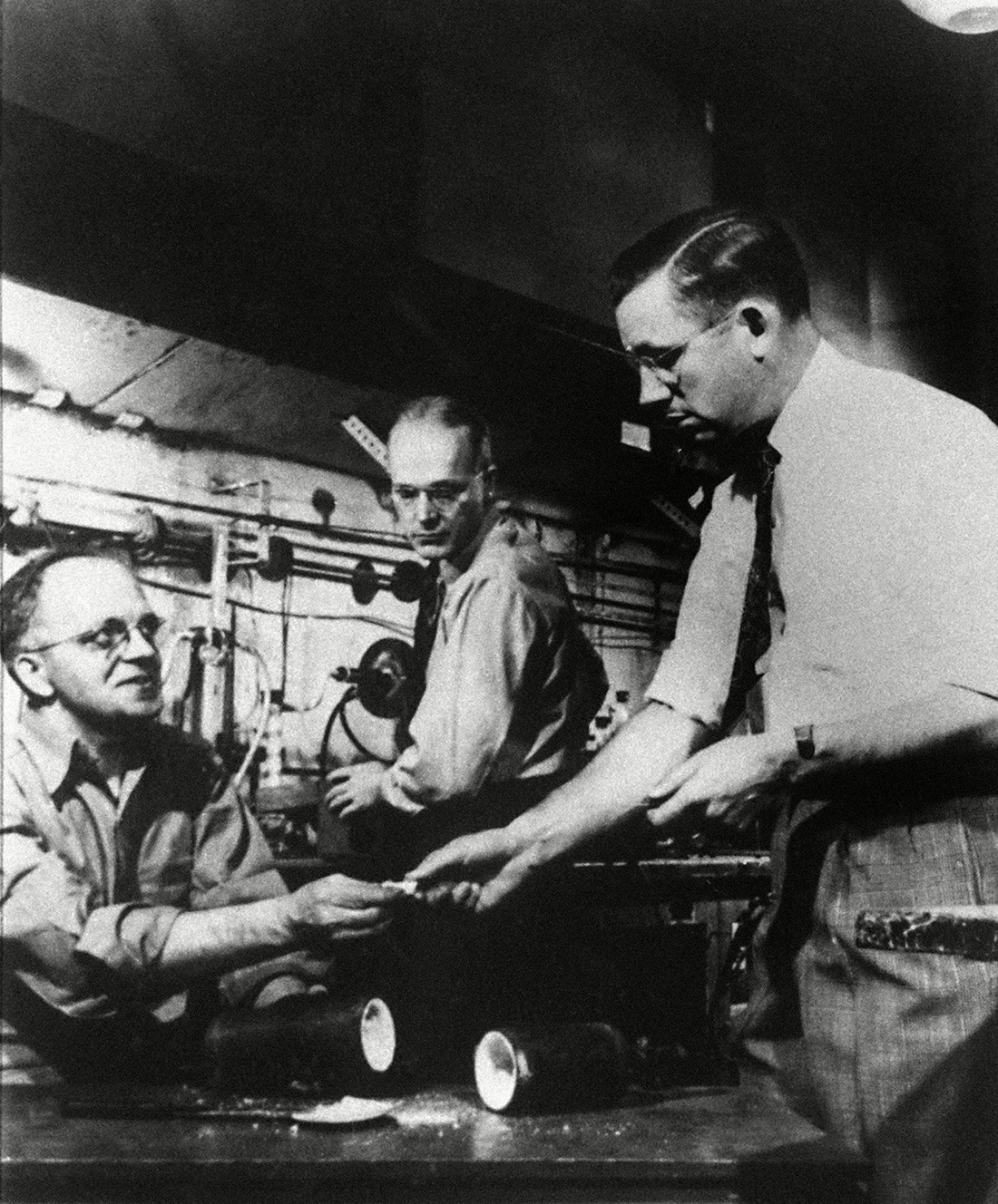 Dr. Roy J. Plunkett, right, holder of the original patent for Teflon, poses with his product and DuPont chemists re-enact the making of the product in one of the company's laboratory. Photo: AP/Shutterstock (6650656a)